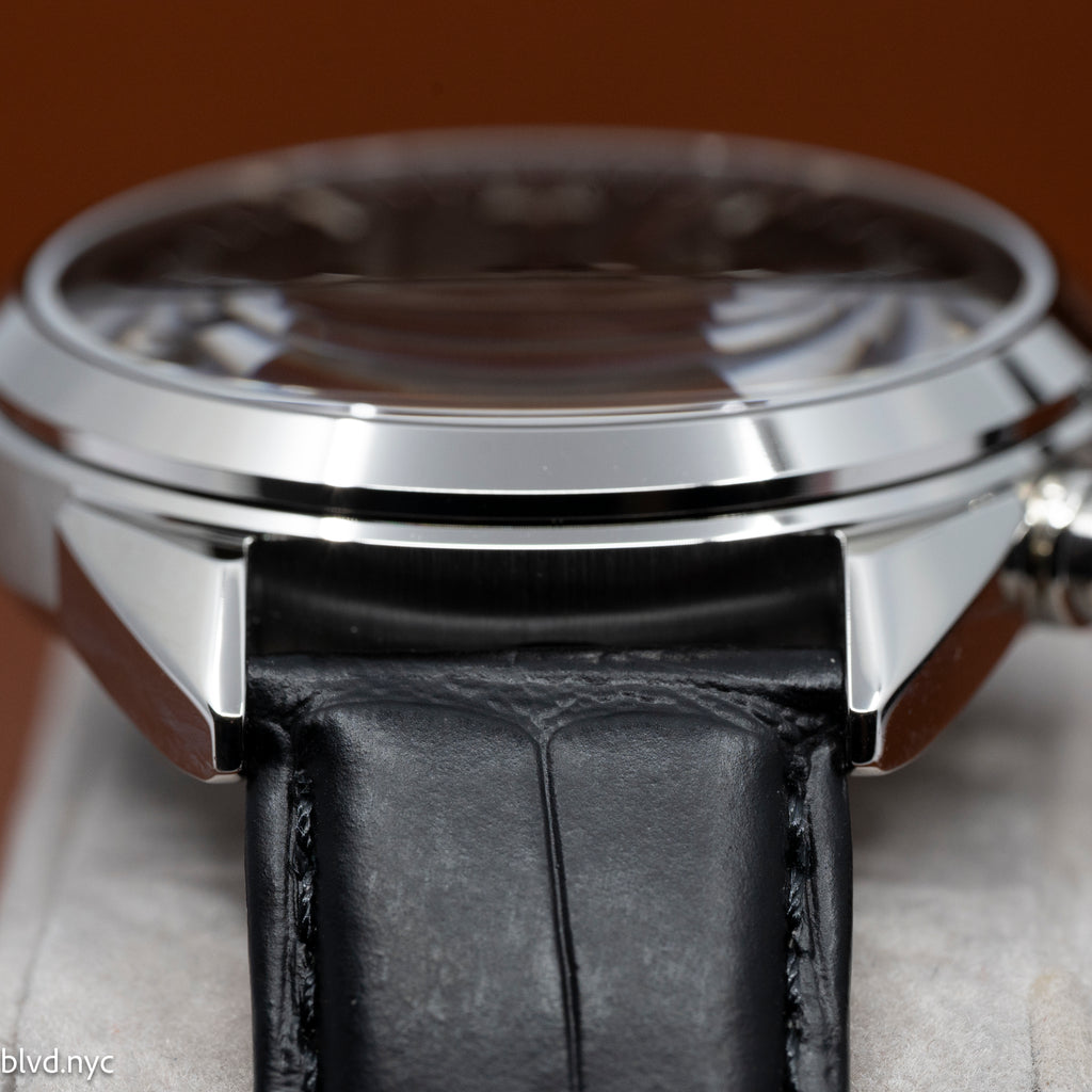 Close-up of a watch with a black leather strap and silver case.