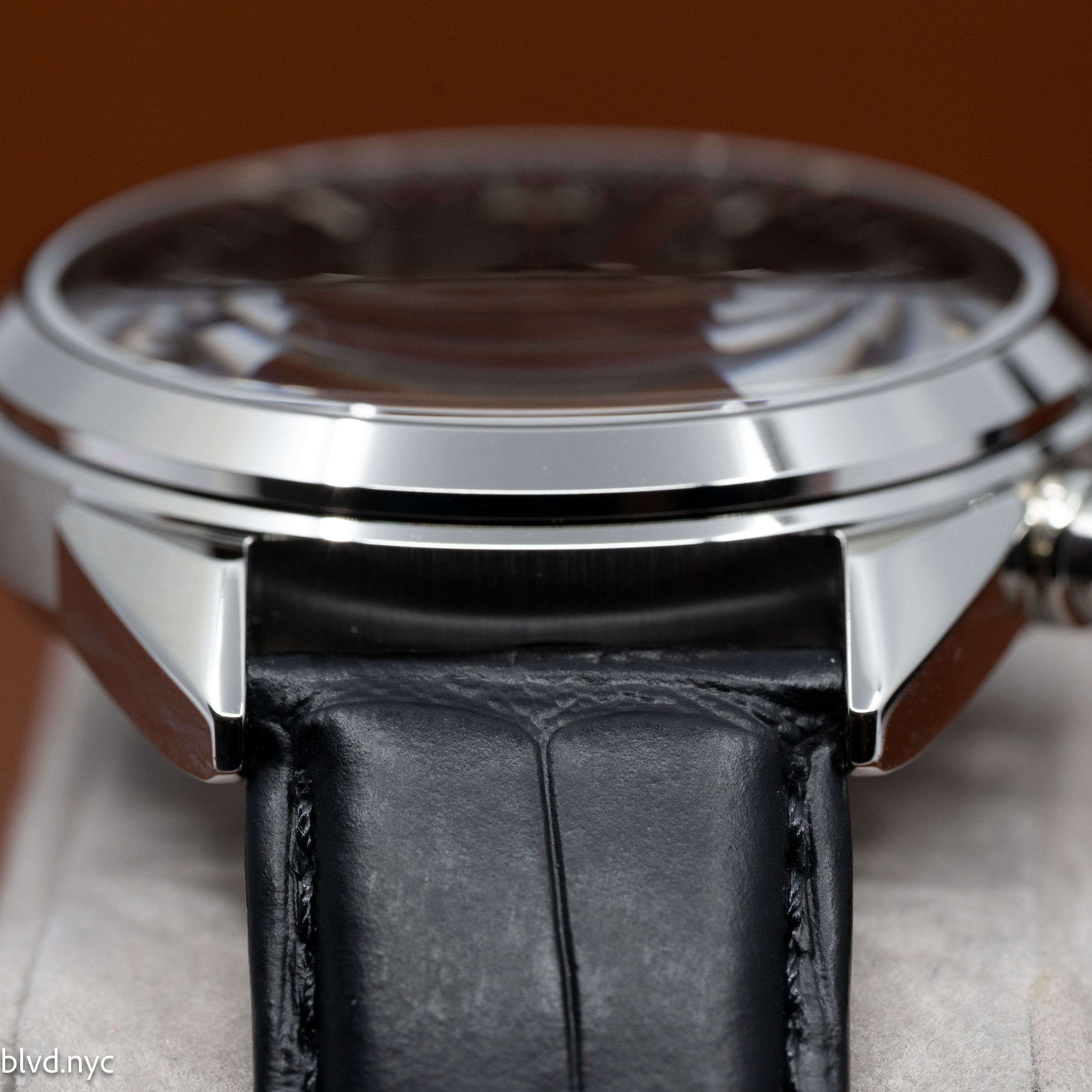 Close-up of a watch with a black leather strap and silver case.